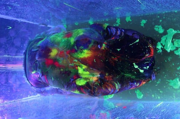 A body painted in fluorescent colour lit by UV light.