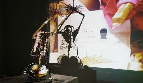 An installation of suspended objects beside a projected figure.