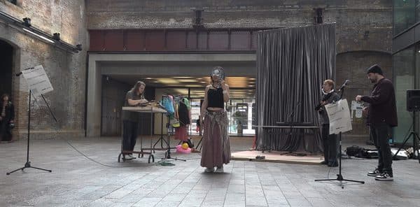Performers and musicians improvising in an industrial gallery space.