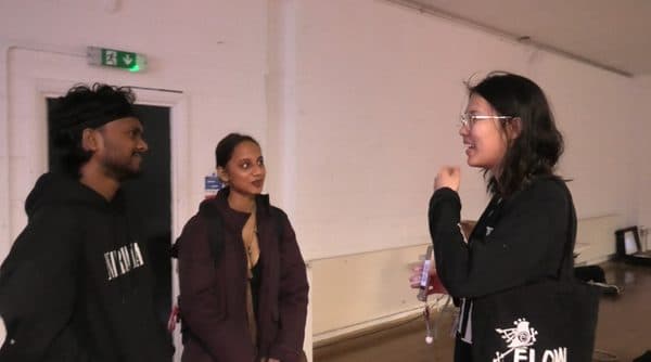 A performer talking with visitors beside an open suitcase.