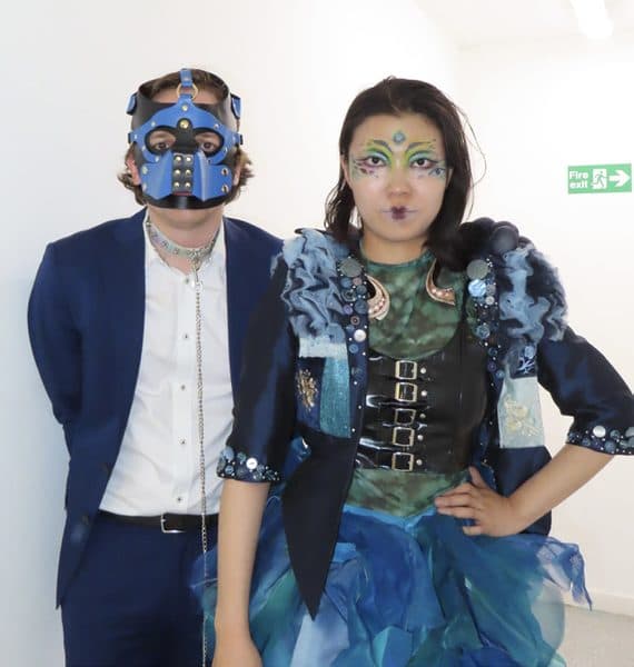 Two performers in elaborate blue peacock-inspired masks and costume.