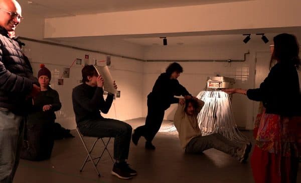 Visitors watching a performance in a gallery space.