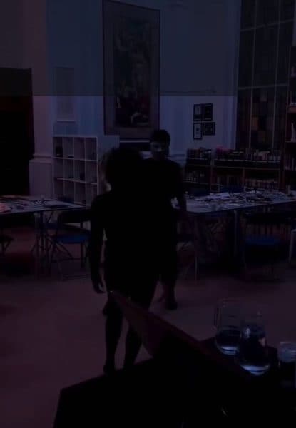 A dim room with a figure silhouetted against a table of papers.