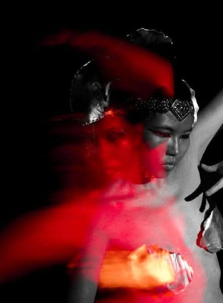 A red-lit, motion-blurred portrait of a performer.