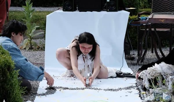 Participants working together on a white groundsheet outdoors.